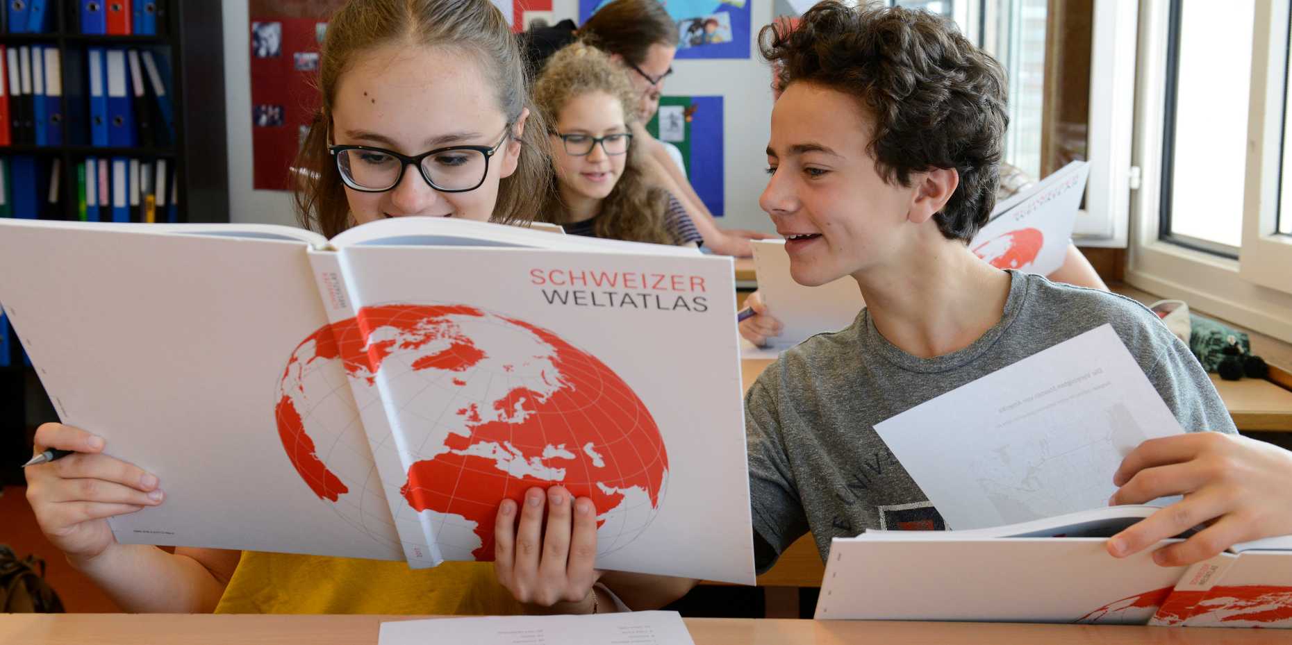 Schüler blättern im neuen Schweizer Weltlatlas