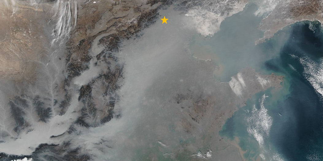 Vergrösserte Ansicht: Grauer Smog bedeckt weite Teile Ostchinas im Januar 2017. Peking liegt nordwestlich der Bucht von Bohai (oranger Stern). (Bild: Nasa Earth Observatory)