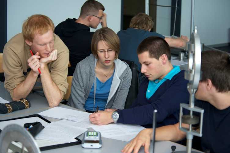 Studierende sitzen am Tisch und lösen Physik-Aufgaben