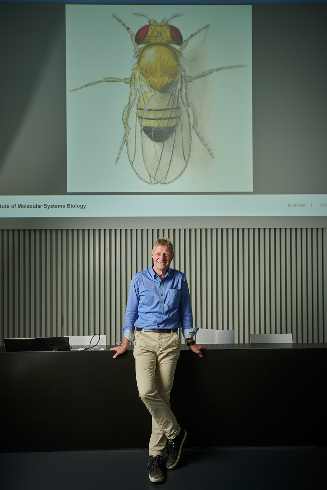 Ernst Hafen in front of an illustration of the fruit fly Drosophila