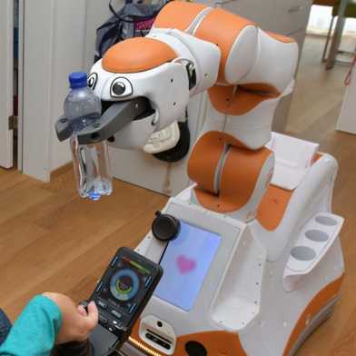 An assistent robot gives a bottle to a woman