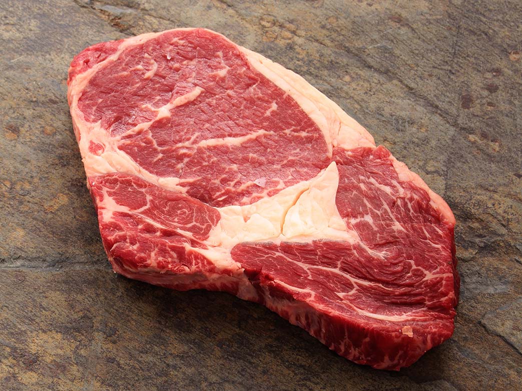 Ribeye steak laying on a wooden ground