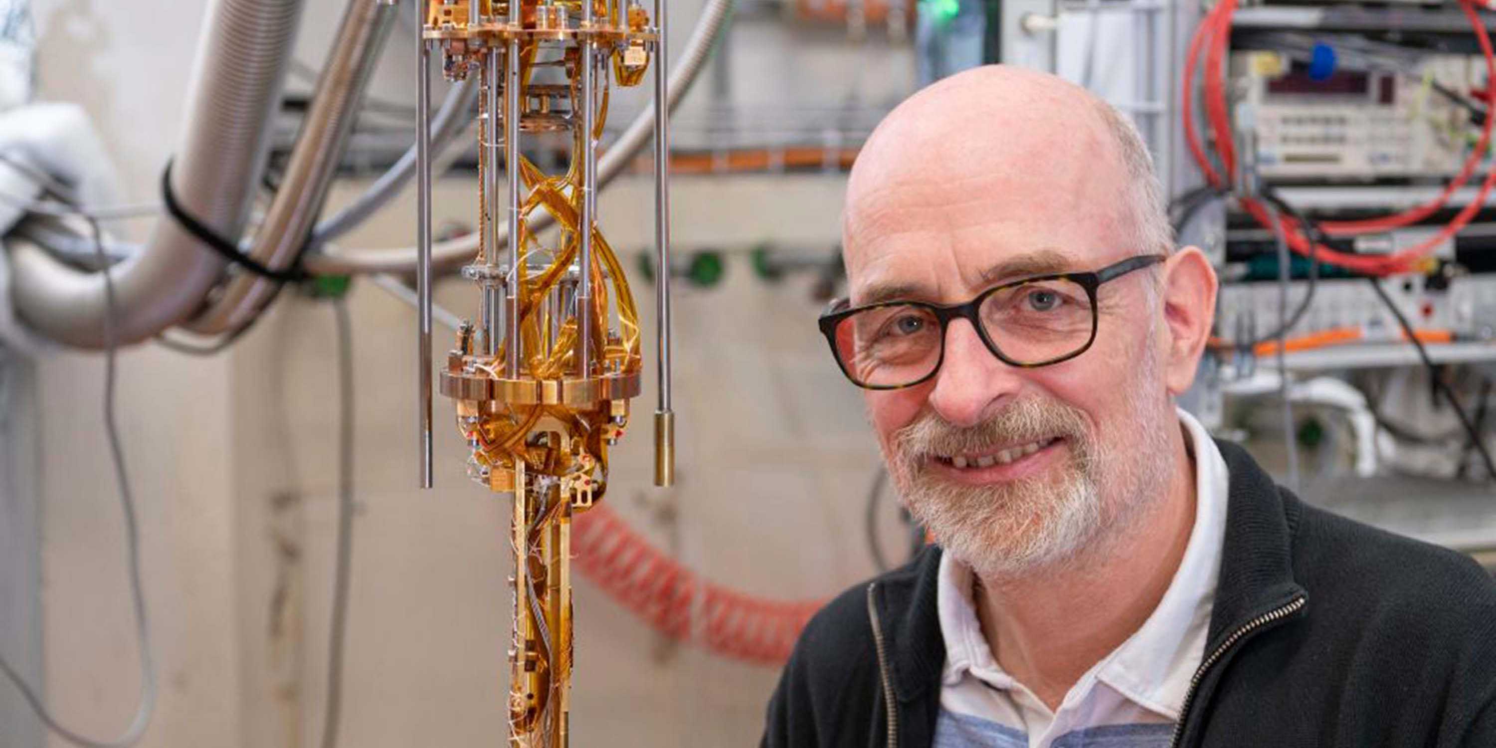 Klaus Ensslin stands smiling in front of a quantum computer