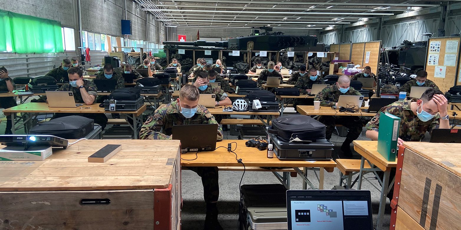 Swiss Army officers working on laptops in a hall