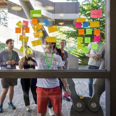 Participants of the ETH Week 2022 discussing in front of colourful post-its on a window pane.