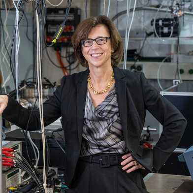 Ursula Keller smiling in front of equipment in her laboratory
