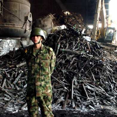 A Colombian soldier stands guard in front of a pile of weapons handed over by paramilitary groups.