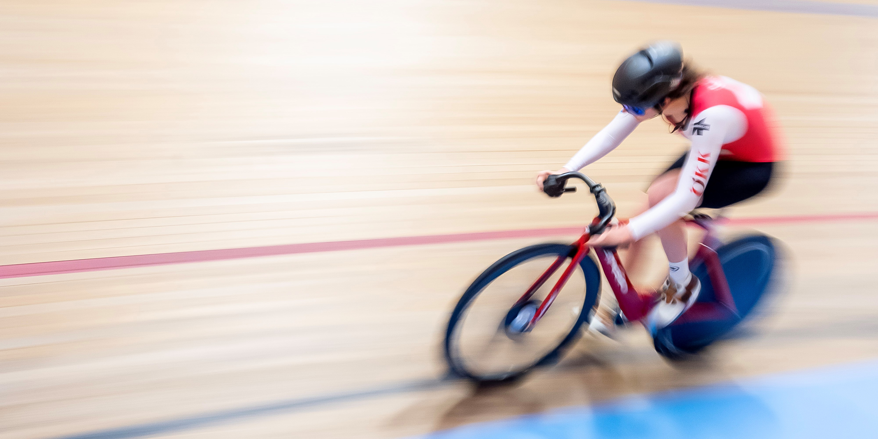 A woman on a racing bike on an indoor race track.