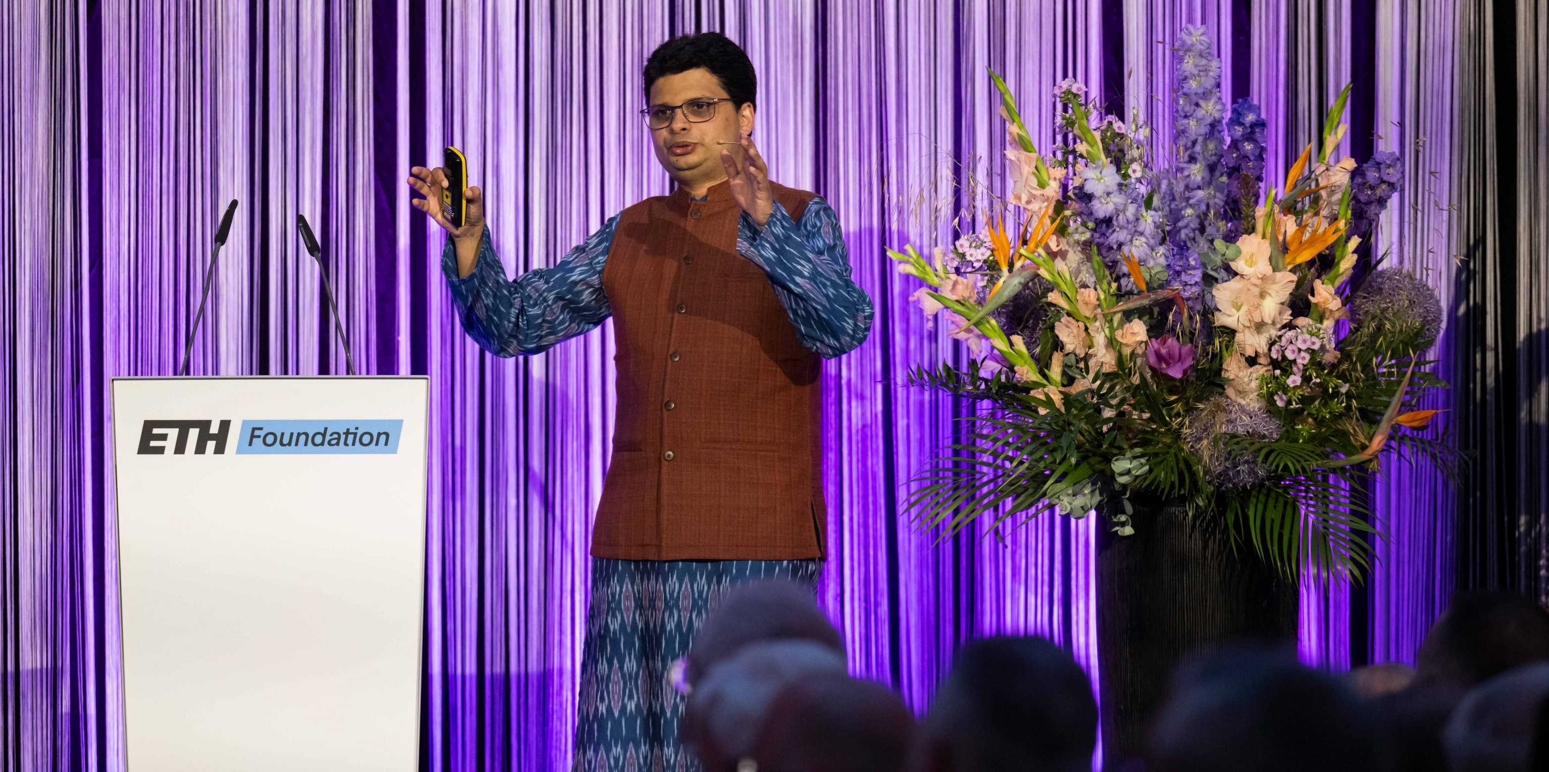 Siddhartha Mishra stands next to a lectern at the ETH Foundation and recites something.