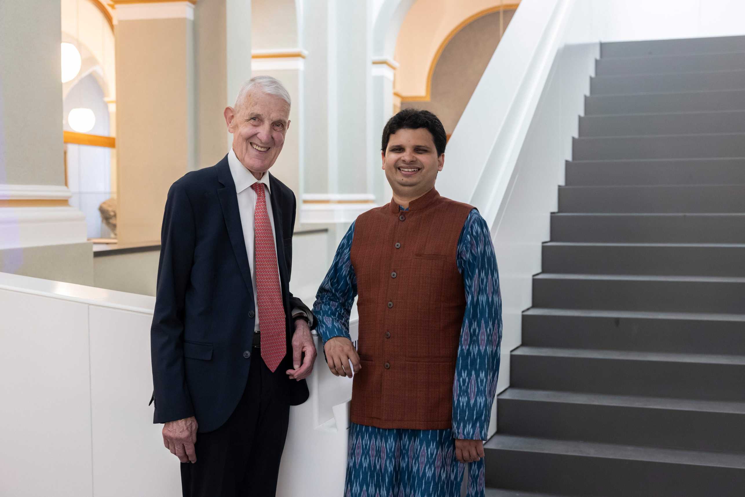 Max Rössler stands next to Siddhartha Mishra in front of a staircase in the ETH building.
