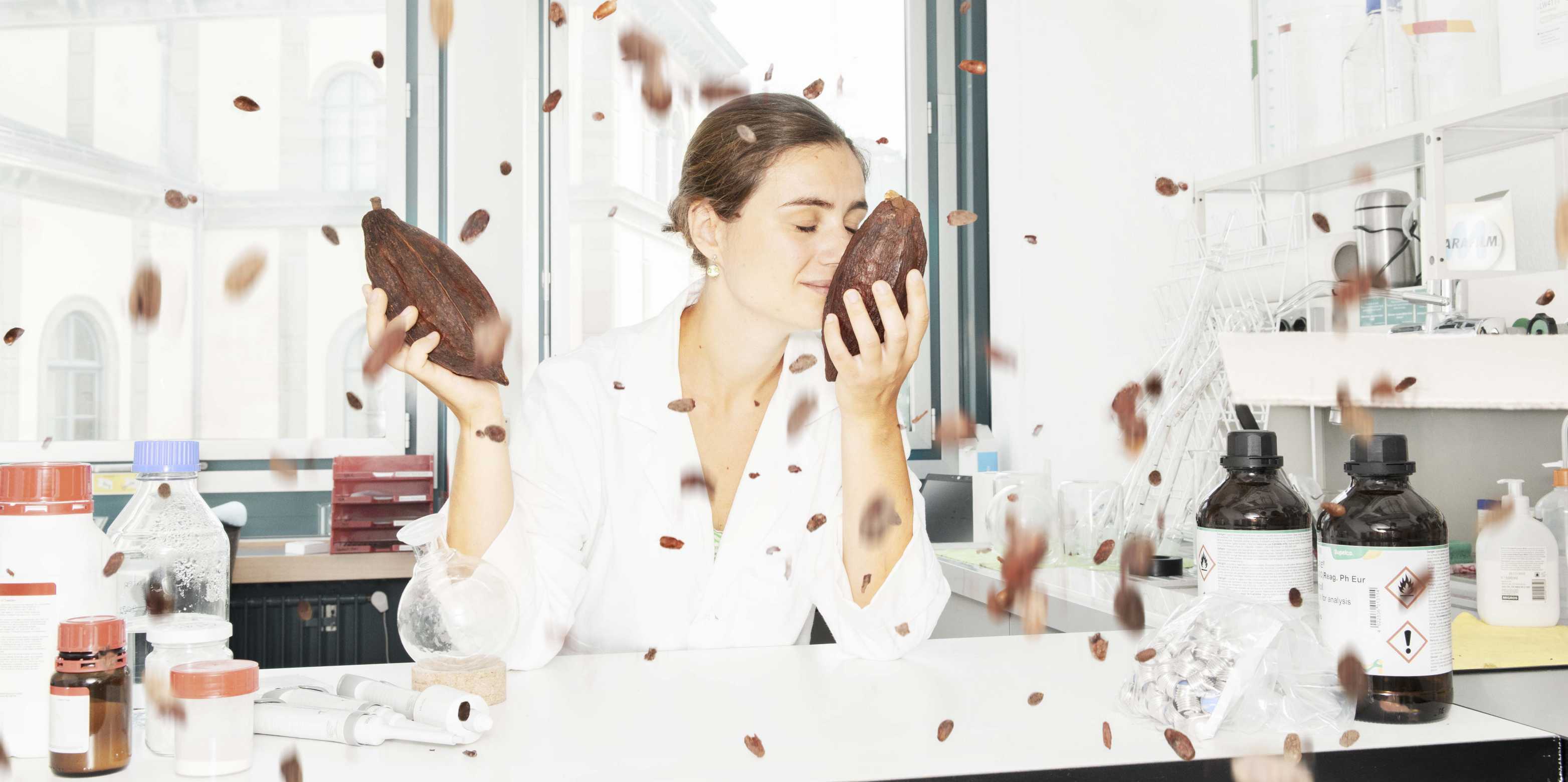 Woman sits in a laboratory and smells a cocoa bean