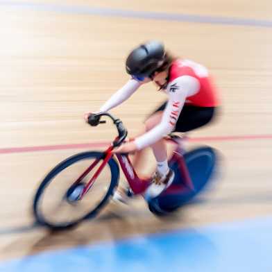 A woman on a racing bike on an indoor cycling track.
