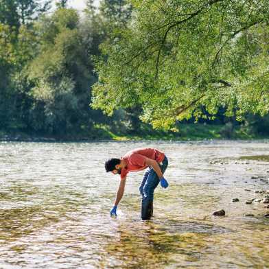 Man stands in the river and takes a water sample