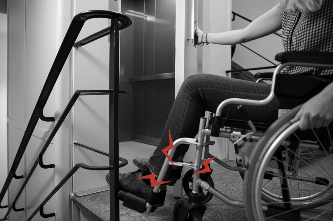 Vergrösserte Ansicht: Eine Person im Rollstuhl kann eine alte Aufzugtür nicht öffnen, da diese mit dem Rollstuhl kollidiert. 
