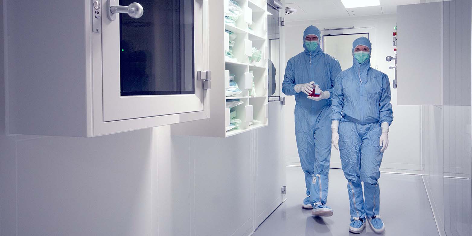 Zwei Forschende der regenerativen Medizin laufen in Ganzkörperanzügen durch das Wyss Zurich Center
