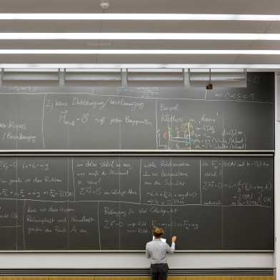 Man standing in front of a blackboard full of writing